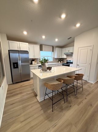 A modern kitchen with a spacious island, white cabinetry, and stainless steel appliances.