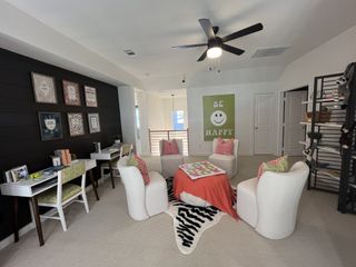 A vibrant loft area with a study space, lounge seating, and motivational wall art in Solterra Texas by Highland Homes (Mesquite, TX).