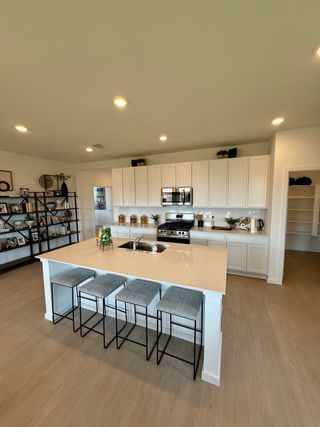 A modern kitchen with sleek white cabinets, central island with seating, and open shelving for stylish storage.