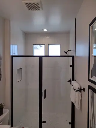 Model Home A sleek bathroom featuring a black-framed glass shower, modern tiles, and ambient lighting.