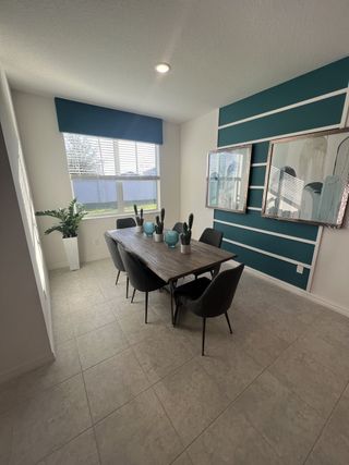 A chic dining space with a bold accent wall, stylish decor, and large windows bringing in natural light.