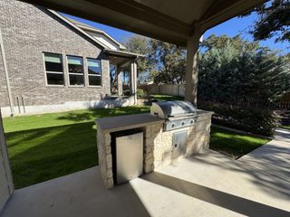 A covered patio with a built-in grill, shaded area, and lush green yard—a perfect outdoor space for entertaining.