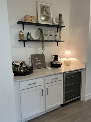 A chic nook with open shelves, wine cooler, and elegant decor, perfect for entertaining or relaxing moments at home.
