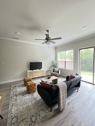 Model Home A cozy living room with a patterned rug, sleek black sofa, and natural light from large windows.