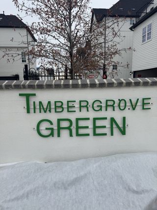 A charming entry into Timbergrove Green by InTown Homes featuring elegant signage amid a serene residential backdrop (Houston, TX).