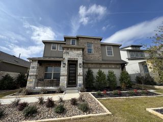 Street view Elegant stone facade home with lush landscaping in Meyer Ranch by Brightland Homes (New Braunfels, TX).
