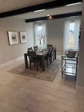 Model Home A cozy dining room with a wooden table, elegant decor, large windows with sheer curtains, and tasteful wall art.