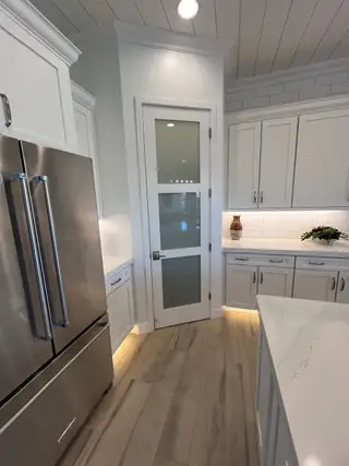 A modern kitchen featuring sleek stainless steel appliances, elegant white cabinetry, and chic wood flooring.