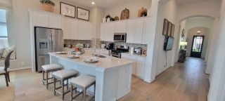 Model Home A modern kitchen with white cabinetry, a stylish island with seating, and chic decor accents.