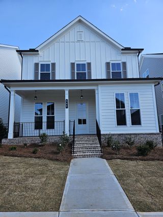 A charming white home with a brick porch in Brackley Single Family by The Providence Group, Cumming, GA.