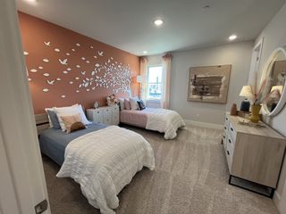 A cozy bedroom featuring twin beds, a nature-themed accent wall, soft lighting, and modern decor.