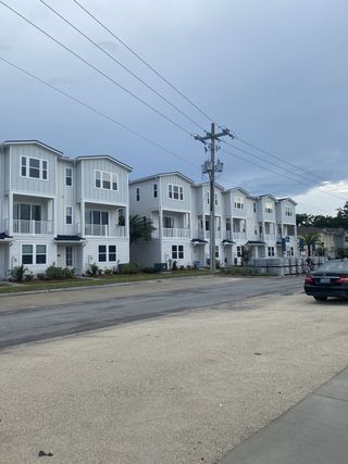 Street view Modern white townhomes with balconies in North Beach Townhomes by Dream Finders Homes, Jacksonville, FL.