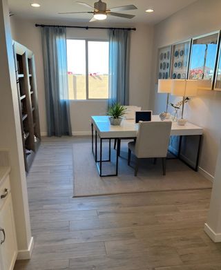 A modern home office with a sleek desk, comfortable chair, and floor-to-ceiling window framed by sheer curtains.
