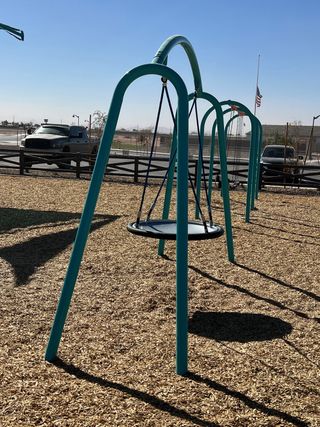 Community Amenities A community playground with modern swings in Rancho Mirage Signature Series by Meritage Homes (Maricopa, AZ).