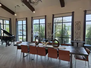 Community Amenities A chic dining area with large windows, a grand piano, elegant decor, and modern leather chairs.