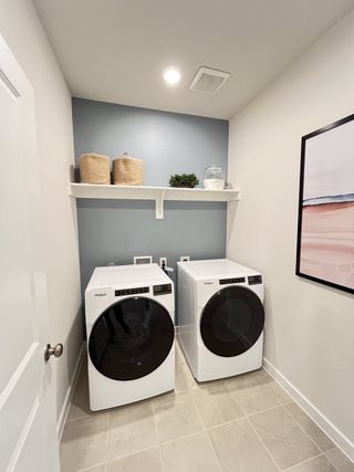 Model Home Modern laundry room with sleek appliances, tile floor, and minimalistic shelving for storage.