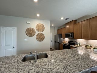 A modern kitchen with granite countertops, wooden cabinets, stainless steel appliances, and stylish decorative accents.