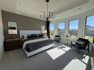 Model Home A serene bedroom featuring a tufted bed, chic lighting, and expansive windows for natural light.