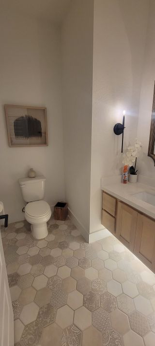A modern bathroom featuring hexagonal patterned tiles, a sleek vanity with understated decor, and soft ambient lighting.