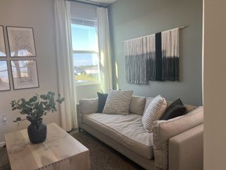 Cozy living area with a plush beige sofa, textured pillows, and modern wall art, illuminated by natural light.