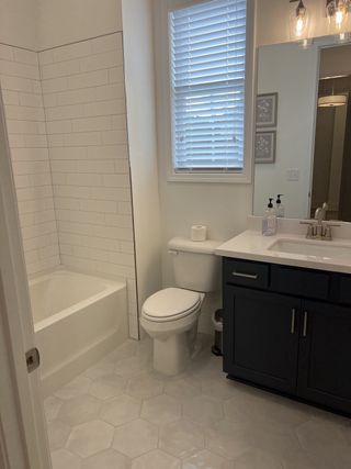 A chic bathroom with subway-tiled shower, hexagonal floor tiles, and a dark vanity with mirror.