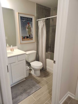 A cozy bathroom with a modern aesthetic, featuring gray tiles, a stylish framed print, and a sleek white vanity.