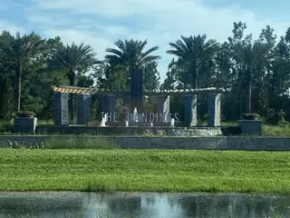 A welcoming entrance with palm trees and stone features at The Landings at Saint Johns by Pulte Homes (St. Johns, FL).