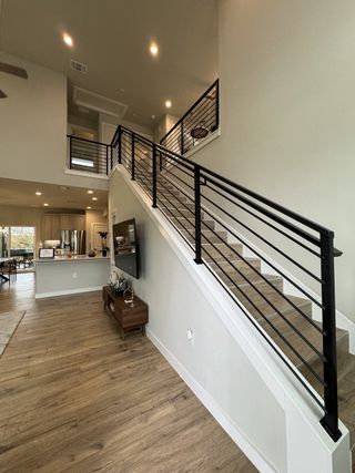 Model Home A stylish interior with wooden floors, sleek black railings, and open spaces, creating a contemporary and inviting atmosphere.