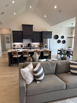 Model Home A modern kitchen with dark cabinets, sleek island, and cozy seating area leading to a stylish dining space.