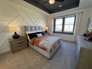 A modern bedroom featuring a geometric accent wall, cozy bed, and large window with natural light.