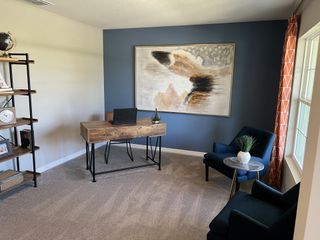 Model Home A sophisticated home office with a bold accent wall, wood desk, and comfortable seating.