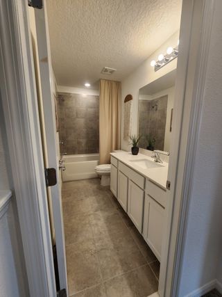 A modern bathroom featuring a tiled bathtub, sleek white vanity, and soft neutral tones for a serene atmosphere.
