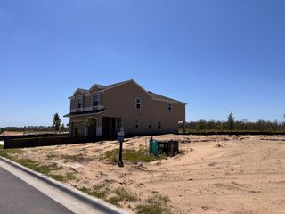 Street view A new beige home with a welcoming porch in Ridgeview by Landsea Homes, Clermont, FL, set against a clear blue sky.