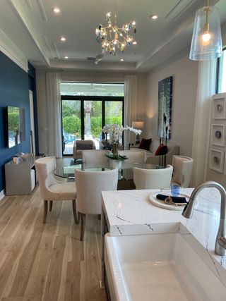 Modern living area with chic chandelier, glass dining table, and elegant decor.