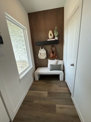 A stylish entryway featuring a slatted accent wall, sleek bench, and warm wood flooring, creating an inviting atmosphere.