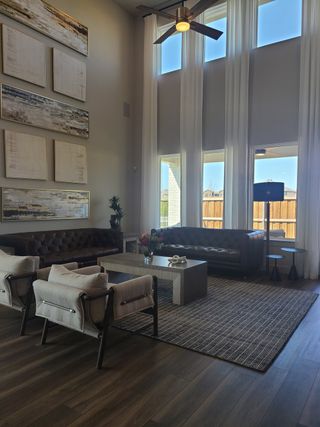 A spacious living room with high ceilings, leather sofas, modern artwork, and floor-to-ceiling windows.