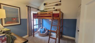 A charming children’s bedroom with a lofted bed, nautical-inspired decor, and cozy seating for a fun and playful space.
