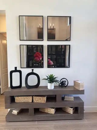 A modern console table with woven baskets, abstract decor, and sleek mirrors above, creating a stylish and functional space.