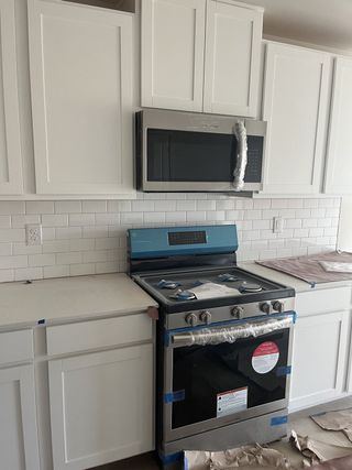 A modern kitchen with white cabinetry, a sleek stainless steel oven, and a subway tile backsplash.