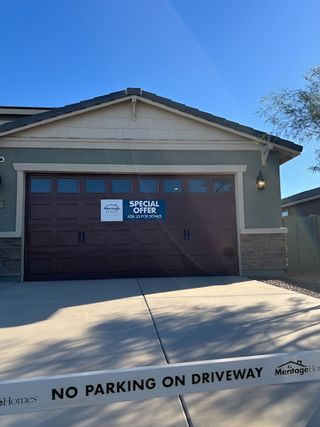 Street view A charming home with a stone-accented facade and spacious driveway in Copper Ridge by Meritage Homes (Maricopa, AZ).
