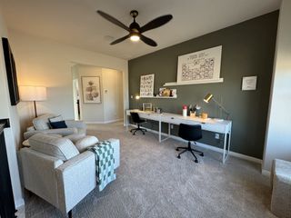 Model Home A cozy home office with a sleek desk, modern chair, and plush seating, featuring subtle decor and ample lighting.