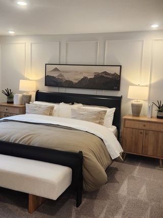A cozy bedroom featuring a sleek bed, neutral bedding, elegant lighting, and nature-inspired artwork for a serene ambiance.
