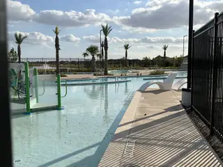 A serene community pool with palm trees and lounge chairs at Marvida Trails South by KB Home in Cypress, TX.