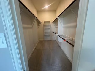 Model Home A spacious walk-in closet featuring ample shelving and hanging space with soft carpet flooring.