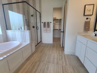 A modern bathroom featuring a glass shower, elegant bathtub, and spacious walk-in closet.