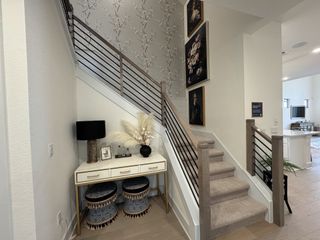 A chic entryway featuring a modern staircase, decorative wallpaper, and elegant furnishings.