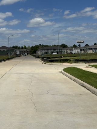 Street view A quiet street with contemporary townhomes under blue skies in Seven Oaks Townhomes by HistoryMaker Homes (Tomball, TX).