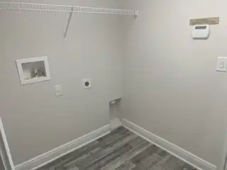 A utility room with wood-style flooring, a wire shelf, and optional security system setup. Clean and functional space.