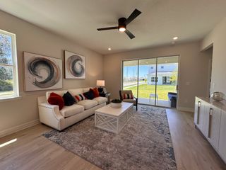 A modern living room with abstract art, plush seating, and sliding glass doors leading to a sunny backyard.