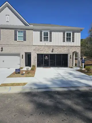 A modern two-story home with gray brick, white accents, and a spacious driveway in River Walk Place by Traton Homes (Lawrenceville, GA).